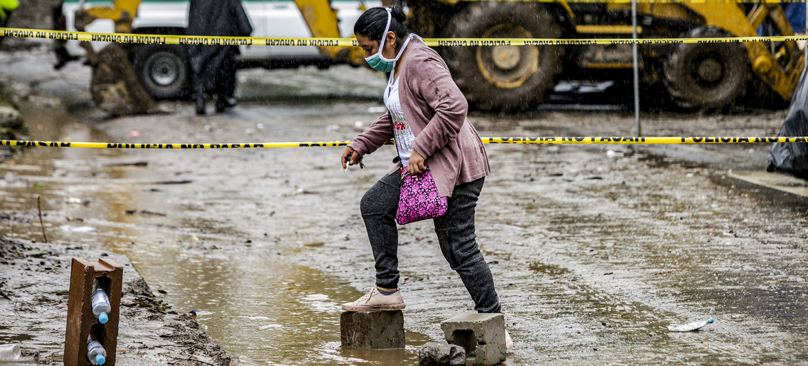 A woman walks across a flooded road in Santo Tomás, San Salvador, after Tropical Storm Amanda caused a landslide.