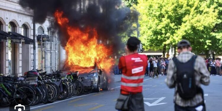 Protesters Set Tesla Ablaze, Smash UN Office’s Windows In Geneva Anti-G7 March